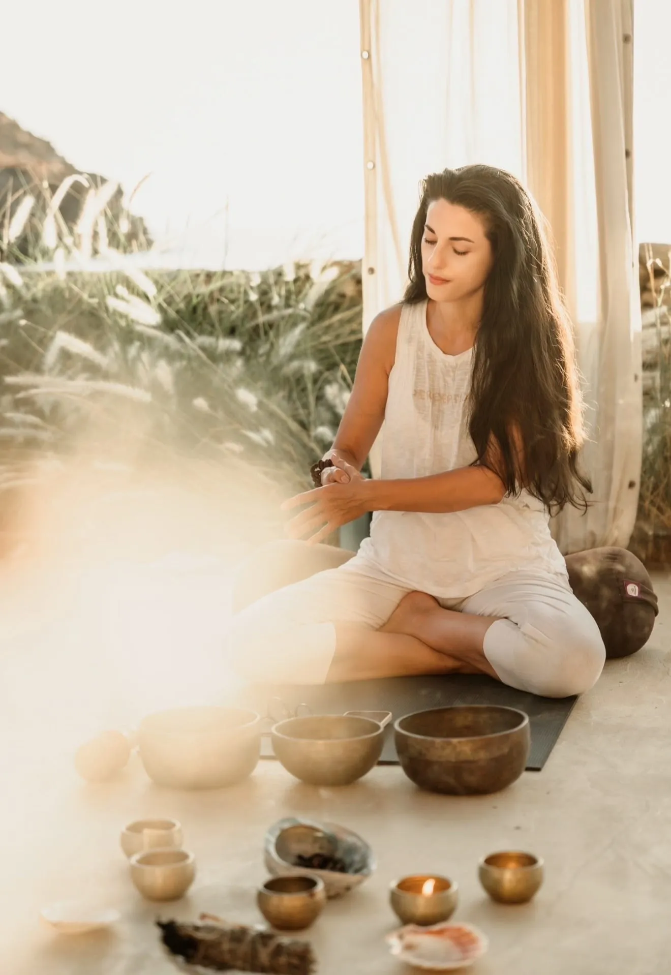 Dalia seated in sunlight with an arrangement of singing bowls