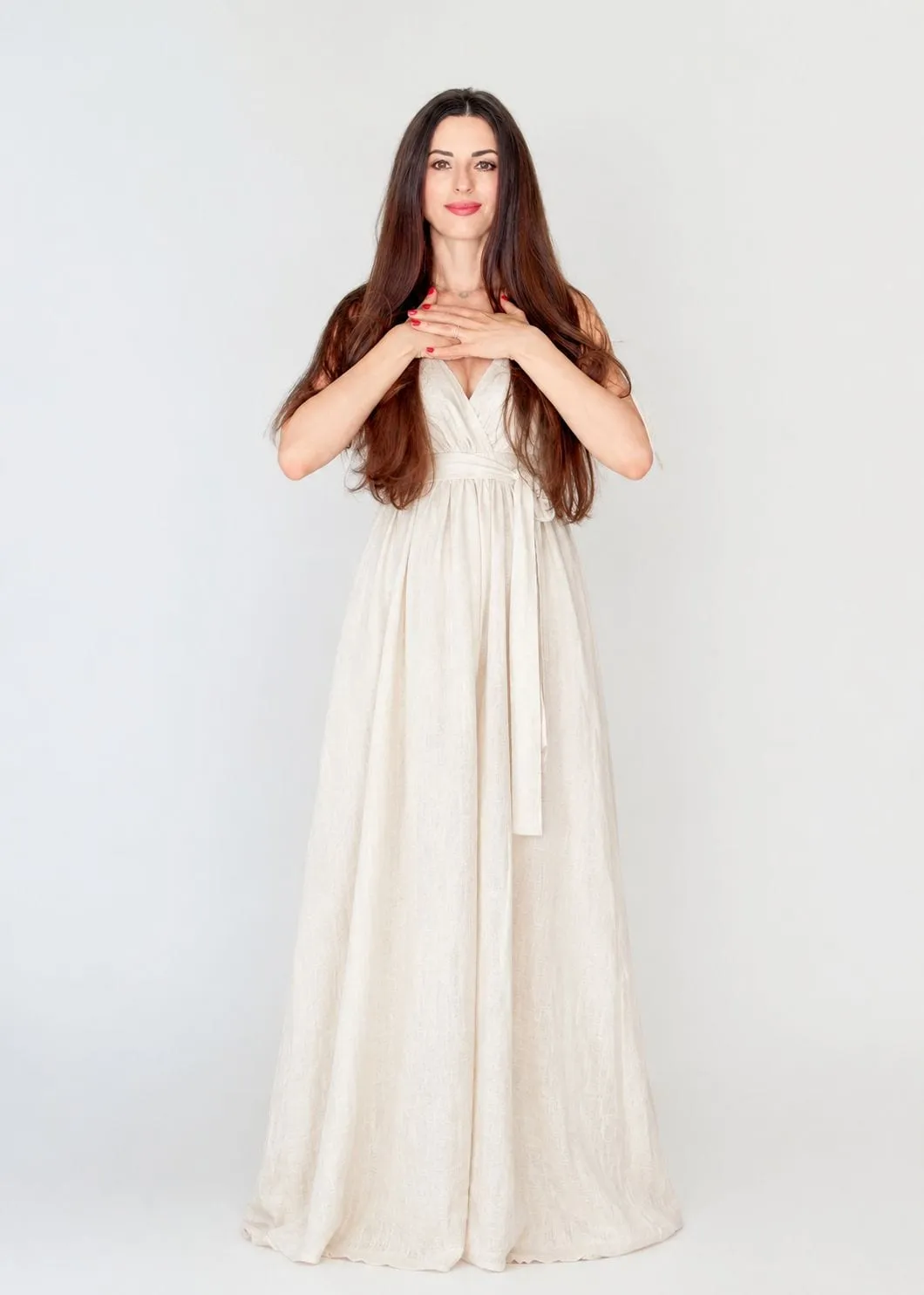 Dalia Lane standing in an ivory linen dress, hands resting at her heart